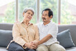 © SKW - Asian couple, elderly man and woman sitting on the sofa having fun chatting together at home. Concept: health insurance, life insurance, retirement happiness.