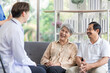 © SKW - Asian couple Elderly men and women sit on sofas having fun and having fun talking with doctors who come to check their health at home.