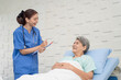 © SKW - A female nurse or doctor is caring for an elderly female patient lying on the patient's bed doing heart and breathing tests. and the patient has a smile