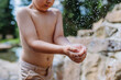 © Halfpoint - Close up of little boy playing outside with water, splashing.