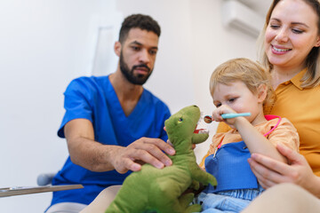 Wall Mural - young dentist showing little girl how to clean teeth on soft toy.