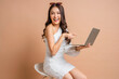 © whyframeshot - attractive positive asia female woman sti on stool hand using laptop social media surfing with enjoy moment toothy smiling studio shot on brown colour background,stylish woman using laptop with love