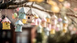 Easter decoration featuring a cluster of pastel-colored birdhouses, hanging from a tree branch with a soft-focus garden background.