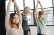 © LIGHTFIELD STUDIOS - Young african american woman meditating in Crescent Lunge asana near blurred group in yoga studio.