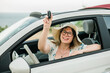 © satura_ - Travelling woman holding keys to new car and smiling at camera - ownership and purchase automobile concept