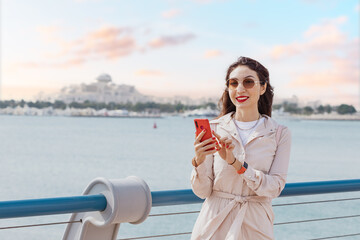 Wall Mural - A Global Lifestyle: In Abu Dhabi, smartphones are ubiquitous, with resident girl staying connected with friends and the world beyond. The city cosmopolitan vibe and global network