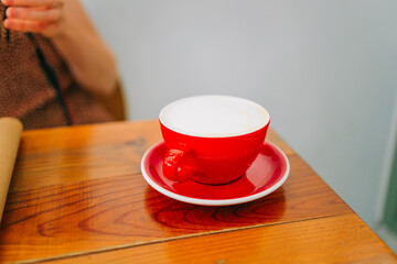 Wall Mural - Red barista cup of coffe in a wooden table at city cafe. High quality photo