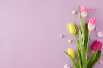 Wall Mural - Mother's Day mood concept. Top view composition of bouquet of pink yellow tulips and colorful hearts baubles on isolated violet background with copy space