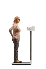 Sticker - Full length profile shot of a woman checking her weight on a professional medical scale