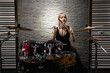 © Georgi - Young cute blonde girl in wireless earphones playing drums drums in a garage. female drummer. musician.