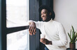 © BullRun - Cheerful black man looking out of window in cafeteria
