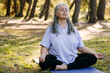 Mindful senior woman with dreadlocks meditating on nature - wellness and yoga practice