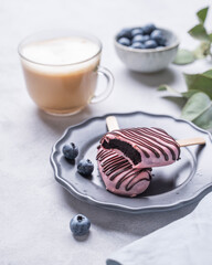 Wall Mural - Cappuccino or latte with milk foam in a cup with handmade berry cakes and blueberries on a light background with eucalyptus branches.