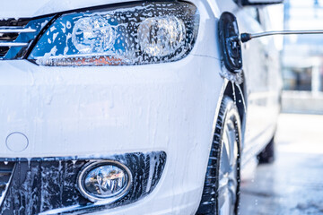 Canvas Print - Manual car wash with white soap, foam on the body. Washing Car Using High Pressure Water.