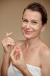 © DragonImages - Smiling mature woman applying lip balm after morning shower