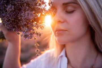 Close-up portrait of young woman with bouquet of purple lavender in front of face. Allergy concept.