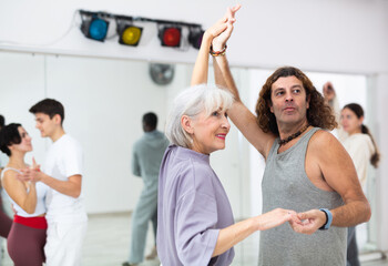 Wall Mural - Caucasian man and mature woman learning paired latin dances