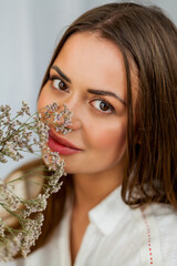 Portrait of beautiful young woman with long hair on white background with dried flowers. Spring.