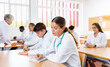© JackF - Girl medical student sitting at desk in classroom during lecture in medical college with group of students.