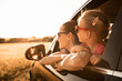 Happy family road trip, mother and daughter looking out of car window enjoying nature view 