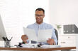 © New Africa - Happy businessman working with documents at wooden table in office