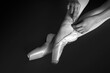 Ballerina tying pointe shoes, top view. Black and white effect