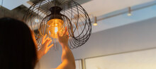 Woman Changing Light Bulb In Hanging Lamp At Home, House Owner Cleaning Or Changing Vintage Light Bulb.