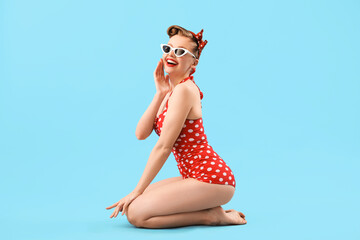 young pin-up woman in polka dot swimsuit on blue background
