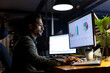 © Wavebreak Media - Biracial businessman sitting at desk, using computers and laptop, working late at office