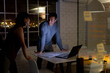 © Wavebreak Media - Diverse business people standing at desk, using laptop and discussing, working late at office