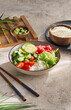 Healthy food - poke bowl with vegetables on light concrete background. Aesthetic composition with veggie bowl in minimal style on beige concrete table. Vegan food menu. Natural food background.