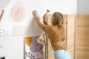 Wall Mural - Young woman nailing on light wall at home