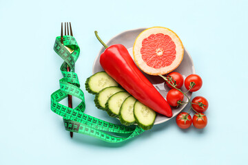 Composition with vegetables, grapefruit and green measuring tape on blue background. Diet concept