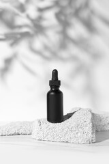 Wall Mural - Empty black tube mockup on pumice stones for cosmetics product presentation. Minimal composition. Vertical studio photography.