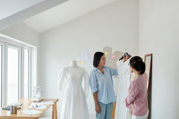 Wall Mural - Tailor showing finished wedding dress to client