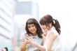 © TAGSTOCK2 - 街中でスマートフォンを見る女性2人