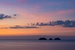 Calm waters of the sea with silhouettes of islands and mountains under the purple sunset sky