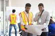 © offsuperphoto - male African engineer and businessman holding white paper blueprint in the office