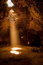 Vertical Shot Of A Lava Tube With Dramatic Sun Rays Inside Cave In Mojave Desert