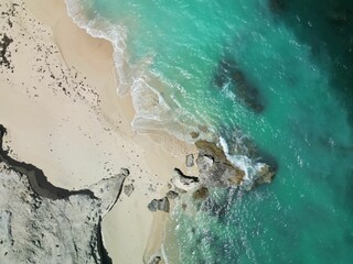 Poster - Scenic view of a beach featuring a rocky outcrop and a tranquil ocean body of water in background