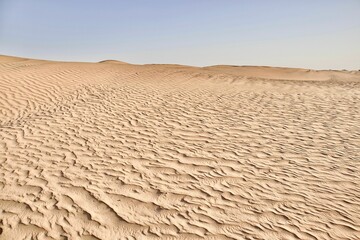 scenic view of desert against sky under the clear blue sky with the sun shining bright