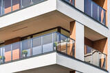 Fototapeta Miasto - Detal na budynek wielorodzinny w centrum miasta. Duża ilość kondygnacji. Balkony i loggie. Duża ilość zieleni dookoła obiektu