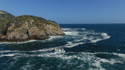 Wall Mural - fishermen boat facing the strong sea in arraial do cabo brazil