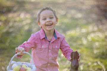 Wall Mural - Beautiful stylish toddler child, boy, playing with Easter decoration in the park