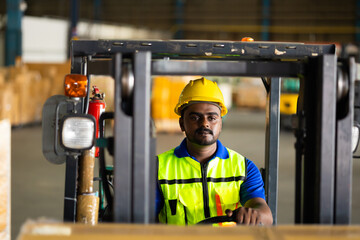 Wall Mural - Indian man worker driving a forklift at warehouse factory. Inventory and wholesale concept. Move pallets and boxes to container