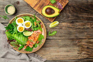 Wall Mural - Salmon fillet with fresh salad, grape, eggs and avocado on a wooden background. set of healthy food for keto diet. Top view