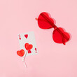 Valentines day creative layout with heart lollipops, playing card and heart sunglasses on pastel pink background. 80s or 90s retro fashion aesthetic love concept. Minimal romantic cosmetic idea.