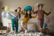 © Halfpoint - Three happy friends having fun with pillows on a bed.
