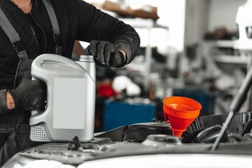 Wall Mural - Close up of car service worker pouring new oil into car engine