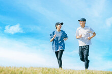 青空の下でジョギングをする笑顔の日本人男女